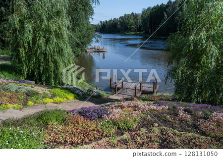 A Serene Lakeside Landscape Showcasing Vibrant Flora, Peaceful Calm Waters and Scenic Views A Serene Lakeside Landscape Showcasing Vibrant Flora, Peaceful Calm Waters and Scenic Views 128131050