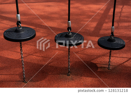 disc swings hanging above red rubber safety surface disc swings hanging above red rubber safety surface 128131218