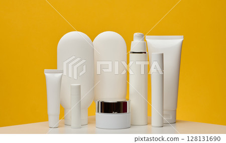 Set of white cosmetic packaging without brand on yellow background. Minimalistic composition for beauty industry, skin care and advertising Set of white cosmetic packaging without brand on yellow background. Minimalistic composition for beauty industry, skin care and advertising 128131690