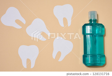 Mouthwash and paper cut out teeth on beige background, oral hygiene Mouthwash and paper cut out teeth on beige background, oral hygiene 128131716