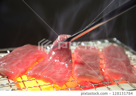 Grilling beef on a charcoal grill with rising smoke Grilling beef on a charcoal grill with rising smoke 128131784