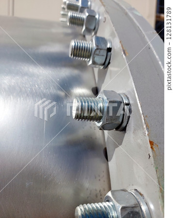 Detailed Close-Up of Flange With Bolts and Nuts in Industrial Setting Under Bright Sunlight Detailed Close-Up of Flange With Bolts and Nuts in Industrial Setting Under Bright Sunlight 128131789