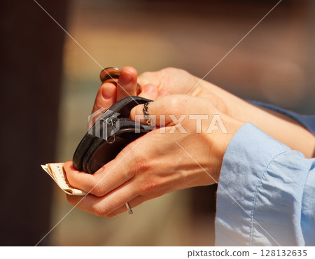 Close-Up of Hands Counting Money and Holding a Small Black Coin Purse Close-Up of Hands Counting Money and Holding a Small Black Coin Purse 128132635