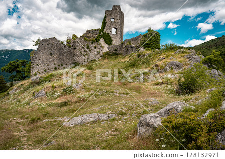 Ruins Of Grad Vipava In Slovenia: Ancient Stone Walls Covered In Ivy Standing On A Grassy Hilltop Under A Dramatic Cloud-Filled Sky In The Scenic Vipava Valley 128132971