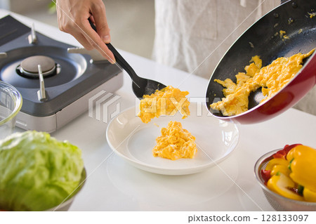 準備雞蛋菜餚的年輕人的手 準備雞蛋菜餚的年輕人的手 128133097