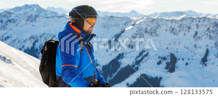 Young adult confident skier portrait at winter alpine skiing resort. Male sporty person with backpack mountain Alps snow slope outdoors cold snowy day Young adult confident skier portrait at winter alpine skiing resort. Male sporty person with backpack mountain Alps snow slope outdoors cold snowy day 128133575