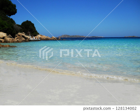 A beautiful beach view that captures the essence of paradise soft golden sands stretch along the shoreline, kissed by gentle waves of crystal-clear, turquoise water. The sun glistens on the surface of A beautiful beach view that captures the essence of paradise soft golden sands stretch along the shoreline, kissed by gentle waves of crystal-clear, turquoise water. The sun glistens on the surface of 128134002