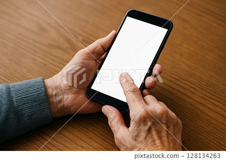 Hands of an elderly person operating a smartphone _ Blank screen 128134263