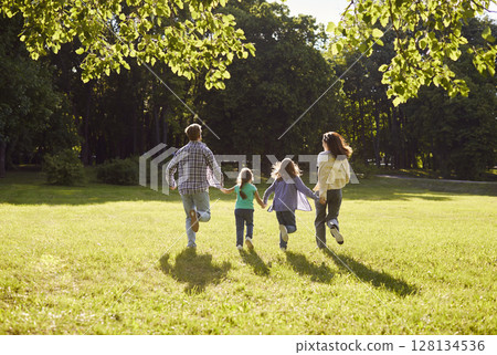 Portrait of family of four with daughter and son running outdoors enjoying beautiful nature. Portrait of family of four with daughter and son running outdoors enjoying beautiful nature. 128134536
