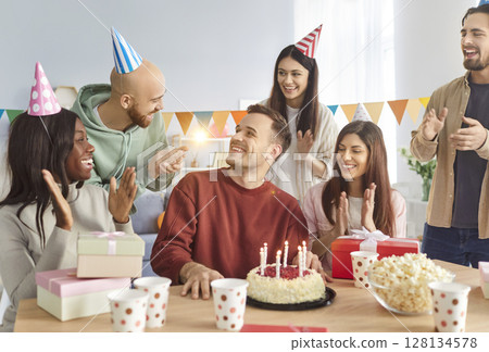 Happy diverse people group sitting at festive table with cake congratulating friend on his Birthday Happy diverse people group sitting at festive table with cake congratulating friend on his Birthday 128134578
