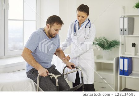 Female caregiver helping to disabled aged male patient walk with walker, physical therapist teaching Female caregiver helping to disabled aged male patient walk with walker, physical therapist teaching 128134593