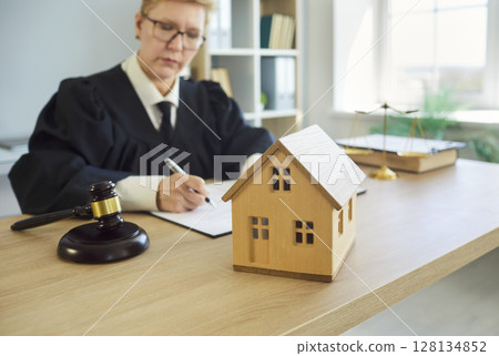 Judge woman in professional outfit black robe writing reviewing house jurisprudence documents Judge woman in professional outfit black robe writing reviewing house jurisprudence documents 128134852