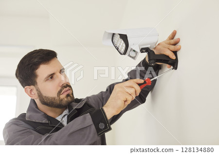 CCTV wall installation connecting bullet camera, worker setting up system for viewing and recording 128134880