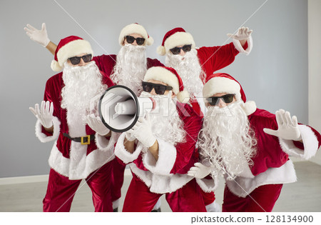 Funny people in Santa Claus costumes shouting announcement in megaphone. Christmas sale concept. 128134900