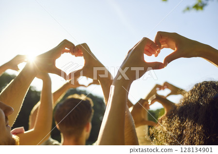 Group of young people friends doing heart gestures against blue sky in summer park Group of young people friends doing heart gestures against blue sky in summer park 128134901