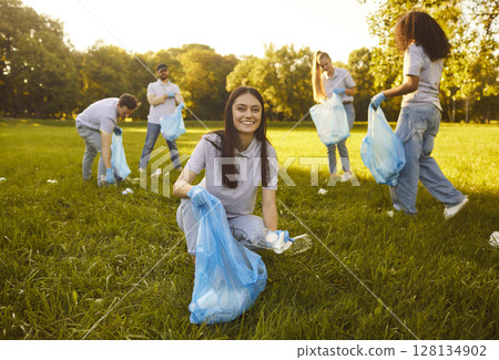 Woman with gloves and trash bag collecting plastic garbage in the summer park Woman with gloves and trash bag collecting plastic garbage in the summer park 128134902