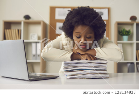 African american woman office worker sleeping on paper document stack at desk African american woman office worker sleeping on paper document stack at desk 128134923