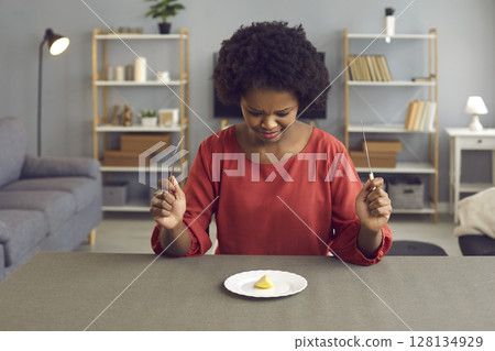 African american woman with disgusting grimace looking at apple piece on plate 128134929