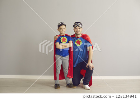 Father and son wearing superhero suit costume looking at camera studio portrait 128134941