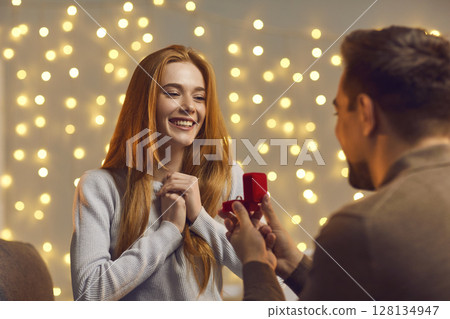 Excited young woman getting and accepting a marriage proposal from her boyfriend 128134947