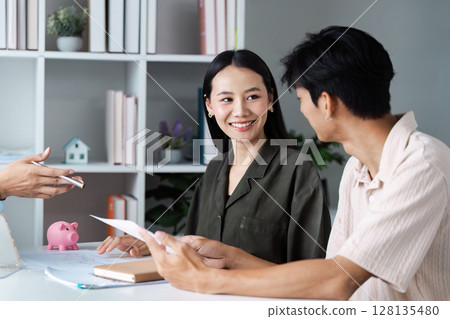 Young Couple Discussing Financial Plan with Professional Advisor in Modern Office Setting 128135480