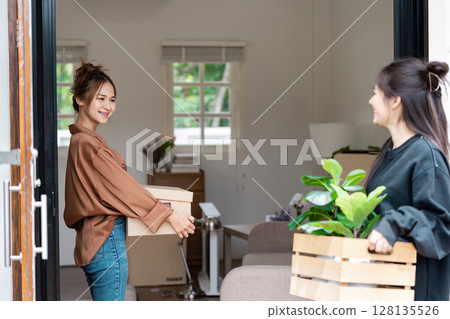 Happy LGBT lesbian Couple Moving into New Home with Boxes and Plants, Embracing New Beginnings and Fresh Start Happy LGBT lesbian Couple Moving into New Home with Boxes and Plants, Embracing New Beginnings and Fresh Start 128135526