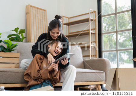 Happy LGBT lesbian Couple Moving into New Home, Unpacking Boxes and Enjoying New Space Together Happy LGBT lesbian Couple Moving into New Home, Unpacking Boxes and Enjoying New Space Together 128135531