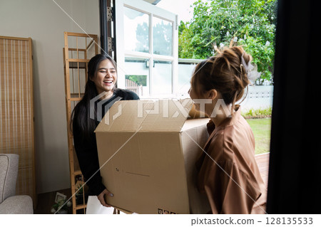 Happy LGBT lesbian Couple Moving into New Home, Carrying Boxes and Smiling, Embracing New Beginnings in Modern House Happy LGBT lesbian Couple Moving into New Home, Carrying Boxes and Smiling, Embracing New Beginnings in Modern House 128135533