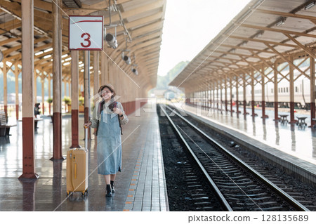Woman with Luggage at Train Station Platform Ready for Travel Adventure, Waiting for Train Arrival, Sunny Day, Wooden Roof Structure, Number 3 Sign, Railway Tracks, Journey Begins Woman with Luggage at Train Station Platform Ready for Travel Adventure, Waiting for Train Arrival, Sunny Day, Wooden Roof Structure, Number 3 Sign, Railway Tracks, Journey Begins 128135689