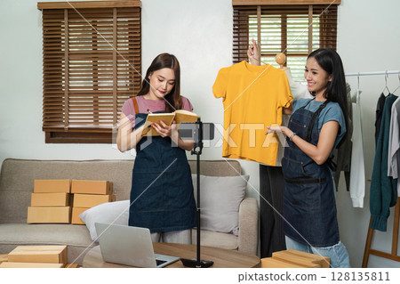 Young Online E-Business Owners Working from Home, Managing Inventory and Creating Content for Their Clothing Store Young Online E-Business Owners Working from Home, Managing Inventory and Creating Content for Their Clothing Store 128135811