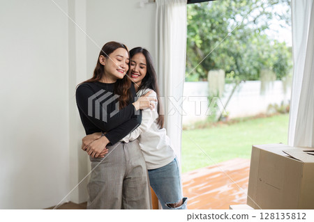 Happy Lesbian Couple Embracing in Their New Home - LGBT Love and Moving Day - Young Women Celebrating New Beginnings Happy Lesbian Couple Embracing in Their New Home - LGBT Love and Moving Day - Young Women Celebrating New Beginnings 128135812