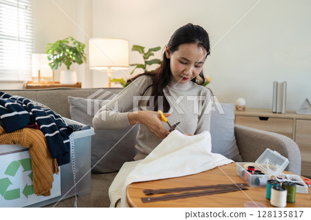 Woman Recycling Old Clothes at Home by Cutting Fabric for DIY Projects, Promoting Sustainable Living and Environmental Conservation Woman Recycling Old Clothes at Home by Cutting Fabric for DIY Projects, Promoting Sustainable Living and Environmental Conservation 128135817