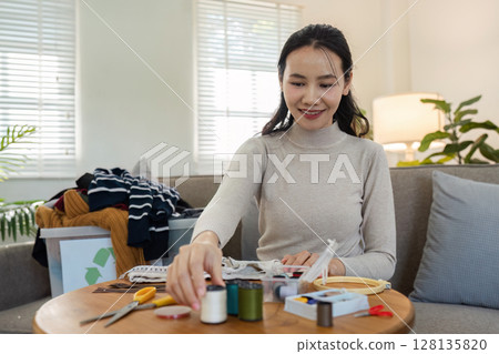 Woman Engaging in Sustainable Practices by Recycling and Upcycling Clothes at Home, Promoting Eco-Friendly Lifestyle and Environmental Conservation 128135820