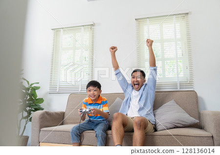 Excitement and Victory. Father and son celebrating while playing video games. 128136014