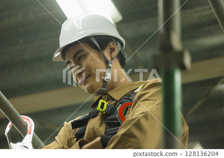 Male worker wearing a full harness 128136204