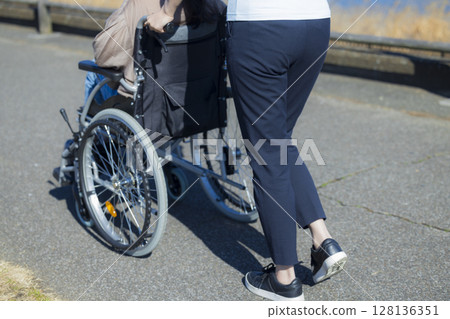 Woman in a wheelchair and her caregiver Woman in a wheelchair and her caregiver 128136351