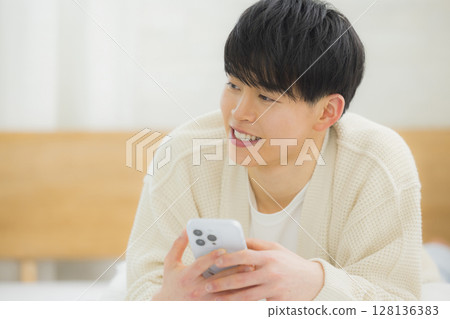 年輕人在床上使用智慧型手機 128136383