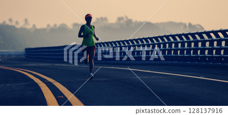 Fitness woman runner running on seaside bridge 128137916