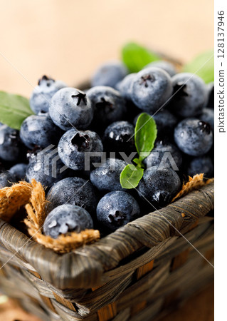 Ripe blueberries in wicker basket on wooden table. Ripe blueberries in wicker basket on wooden table. 128137946