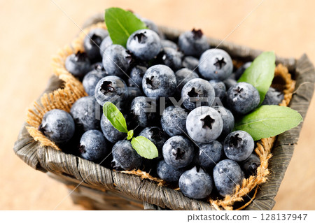 Ripe blueberries in wicker basket on wooden table. Ripe blueberries in wicker basket on wooden table. 128137947