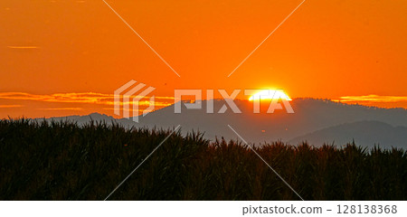 The sun slowly sinks behind the mountain and the crimson sky The sun slowly sinks behind the mountain and the crimson sky 128138368