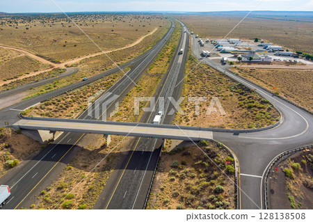 Aerial view of highway interchange in Arizona desert near Fort Defiance bridge overpass crossing divided highway with sparse traffic. 128138508