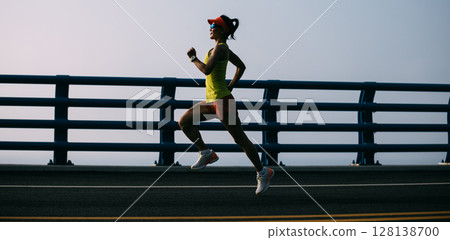 Fitness woman runner running on seaside bridge 128138700