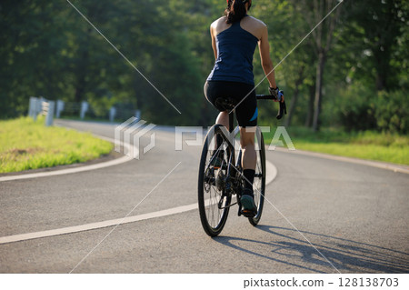 Fitness woman cyclist riding bike in summer park 128138703
