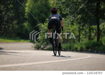 Woman cyclist riding bike at summer park Woman cyclist riding bike at summer park 128138707