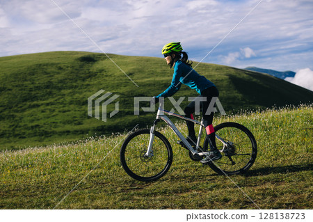 Asian woman riding mountain bike on beautiful mountain top Asian woman riding mountain bike on beautiful mountain top 128138723