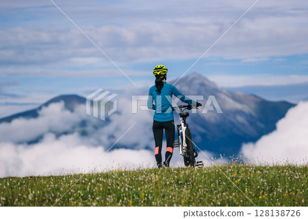 Asian woman riding mountain bike on beautiful mountain top Asian woman riding mountain bike on beautiful mountain top 128138726