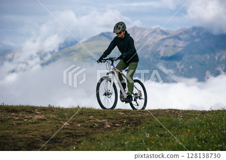 Asian woman riding mountain bike on beautiful mountain top Asian woman riding mountain bike on beautiful mountain top 128138730