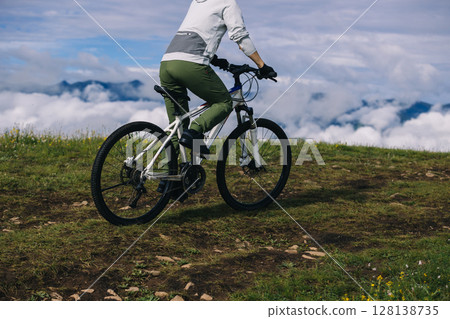 Asian woman riding mountain bike on beautiful mountain top Asian woman riding mountain bike on beautiful mountain top 128138735