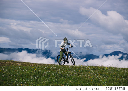 Asian woman riding mountain bike on beautiful mountain top Asian woman riding mountain bike on beautiful mountain top 128138736